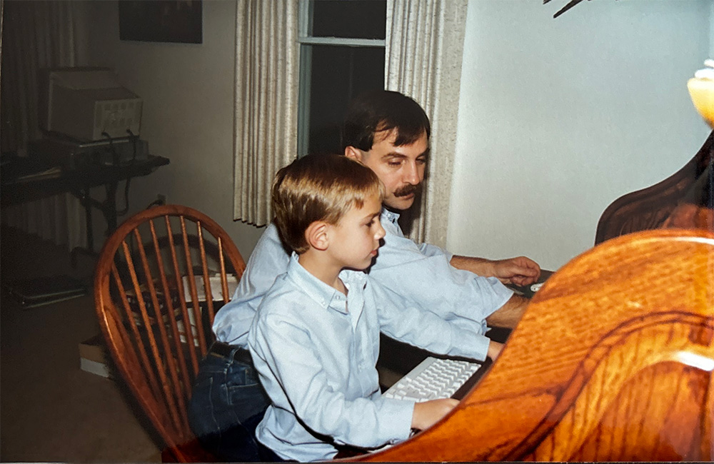 Adrian with his dad at a computer desk